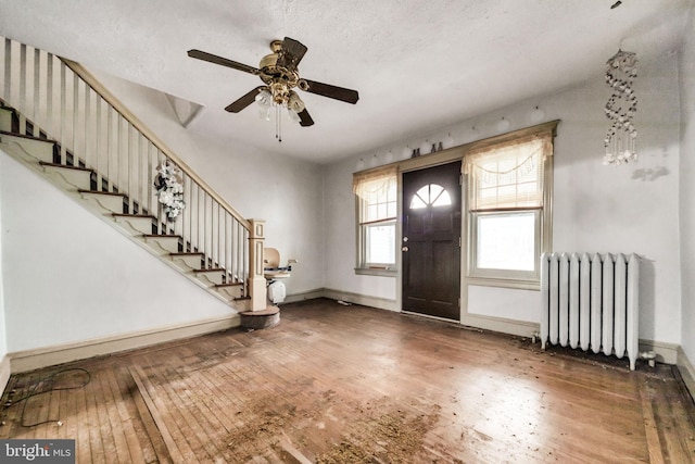 entryway with stairs, hardwood / wood-style flooring, radiator, and ceiling fan