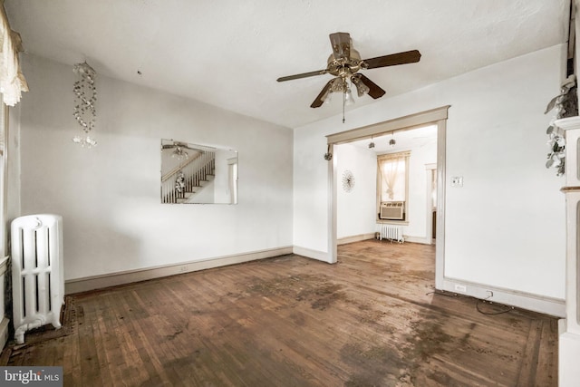 spare room with radiator, wood finished floors, baseboards, and a ceiling fan