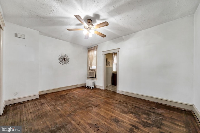 spare room with baseboards, cooling unit, hardwood / wood-style floors, radiator, and ceiling fan