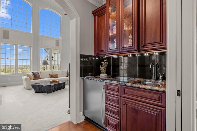 bar featuring a sink, backsplash, baseboards, refrigerator, and arched walkways