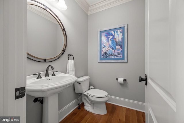 half bathroom with crown molding, toilet, wood finished floors, and baseboards