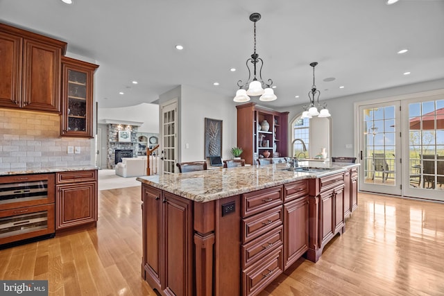kitchen with a wealth of natural light, tasteful backsplash, light wood-style flooring, and a sink