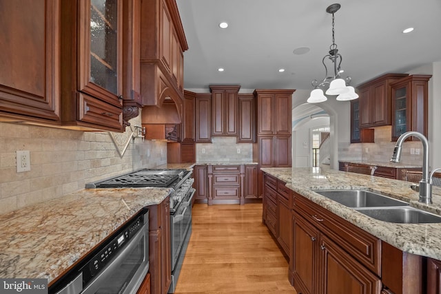 kitchen featuring a sink, arched walkways, high end stainless steel range, and tasteful backsplash