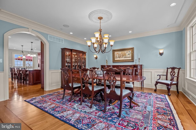 dining space featuring visible vents, a decorative wall, a notable chandelier, and wainscoting