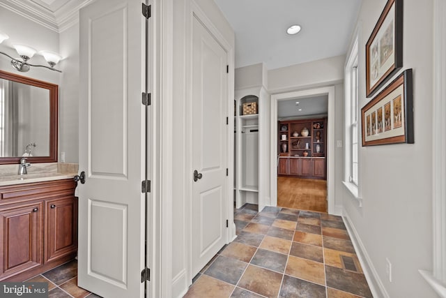 hall featuring stone finish floor, a sink, visible vents, baseboards, and recessed lighting