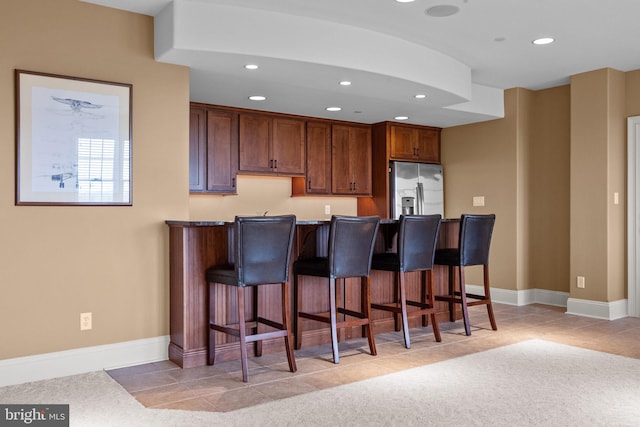 kitchen with stainless steel fridge, a kitchen bar, and recessed lighting