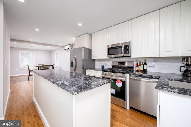 kitchen featuring white cabinets, decorative backsplash, a wall unit AC, and appliances with stainless steel finishes