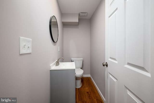 bathroom with toilet, baseboards, vanity, and wood finished floors