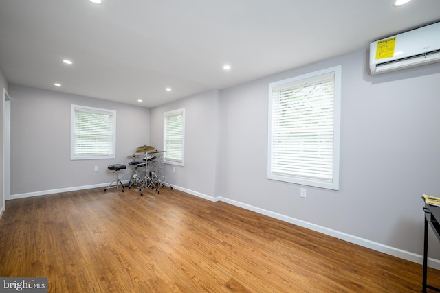 office featuring a wall mounted air conditioner, wood finished floors, and recessed lighting