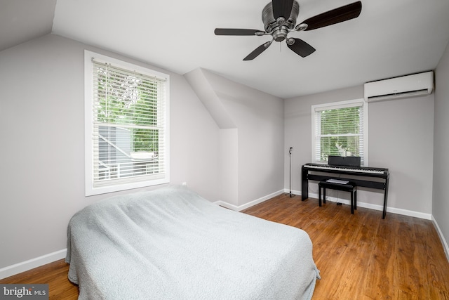 bedroom featuring lofted ceiling, baseboards, wood finished floors, and an AC wall unit