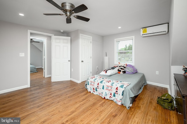 bedroom with recessed lighting, light wood-style flooring, baseboards, and an AC wall unit