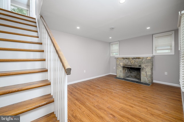 stairway with wood finished floors, a fireplace, baseboards, and recessed lighting