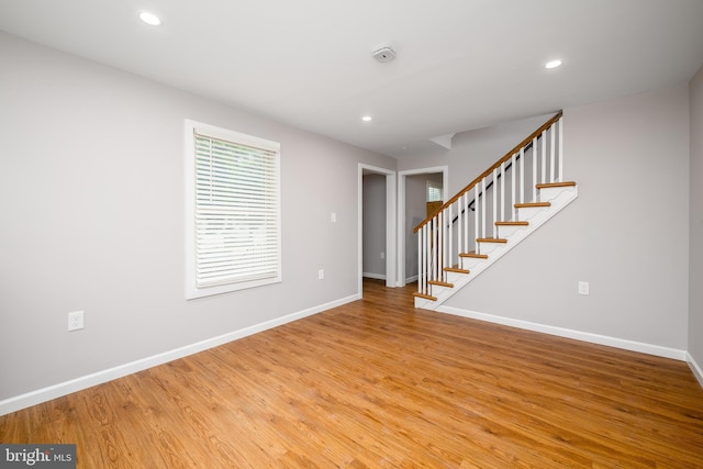 unfurnished living room featuring stairway, wood finished floors, baseboards, and recessed lighting