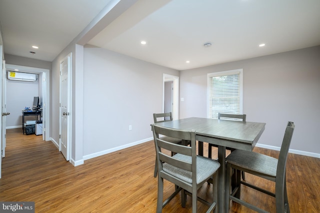 dining room featuring a wall mounted AC, baseboards, light wood-type flooring, and recessed lighting