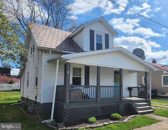 bungalow with roof with shingles, a porch, and a front yard