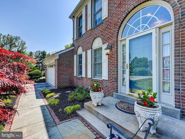 view of exterior entry with brick siding and an attached garage