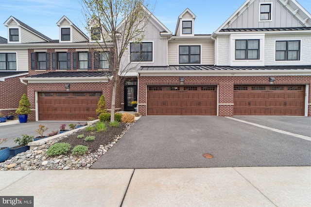 multi unit property with driveway, board and batten siding, a garage, brick siding, and a standing seam roof