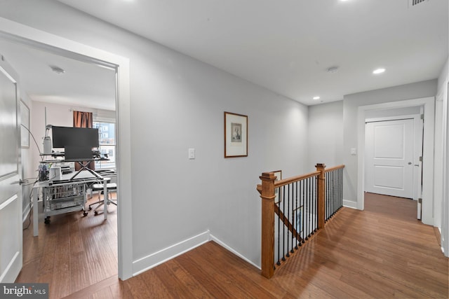 hallway featuring baseboards, wood finished floors, an upstairs landing, and recessed lighting