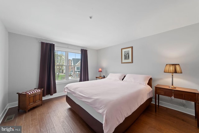 bedroom featuring baseboards, wood finished floors, and visible vents