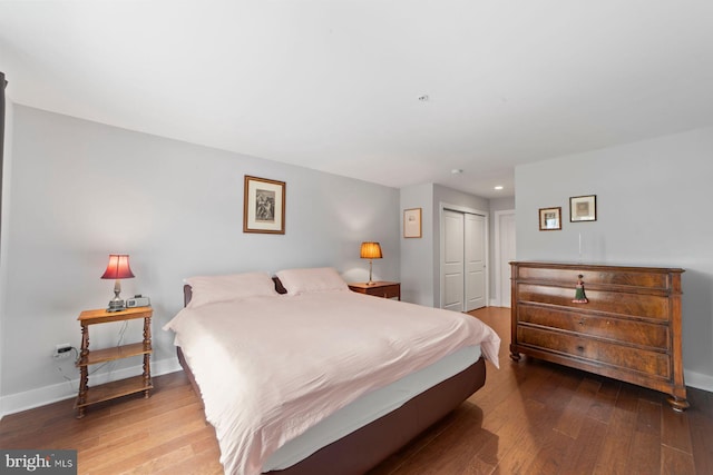 bedroom with wood-type flooring, recessed lighting, baseboards, and a closet
