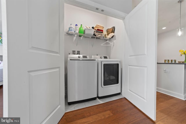 laundry area featuring wood finished floors, washer and clothes dryer, baseboards, and laundry area