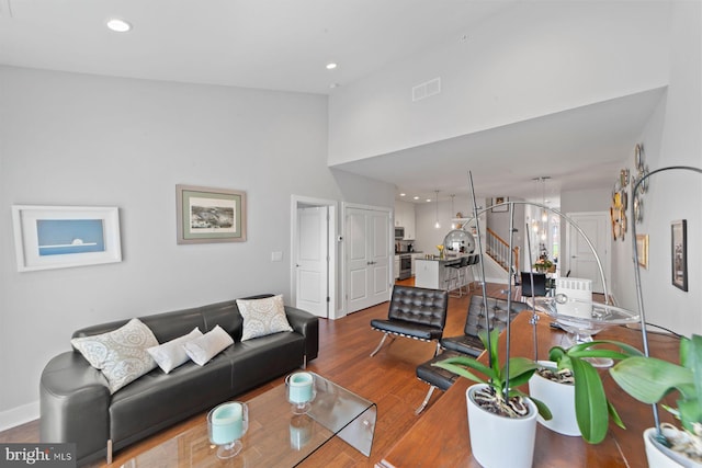 living room featuring high vaulted ceiling, wood finished floors, visible vents, and recessed lighting
