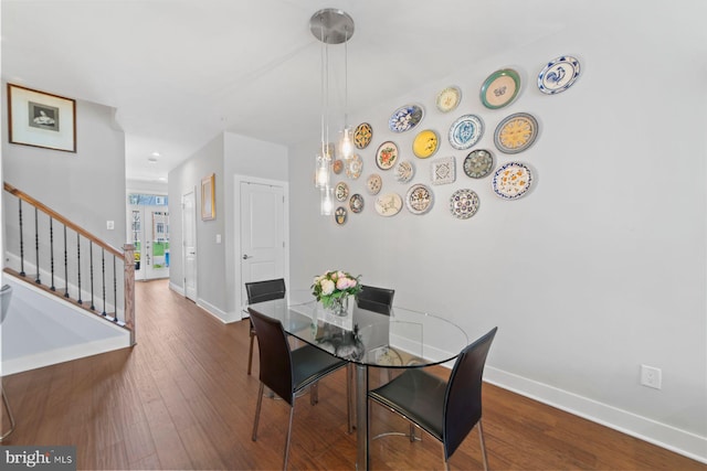 dining space featuring stairway, baseboards, and wood finished floors