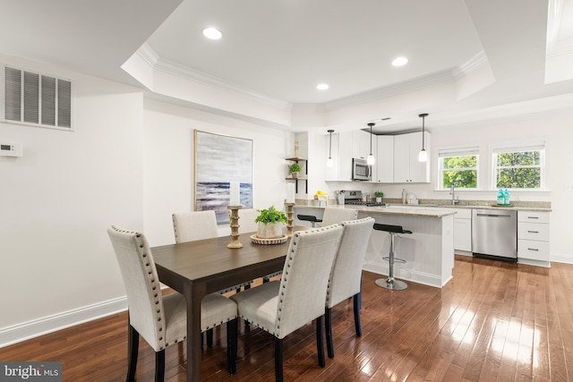 dining space featuring visible vents, ornamental molding, a raised ceiling, and dark wood-style flooring