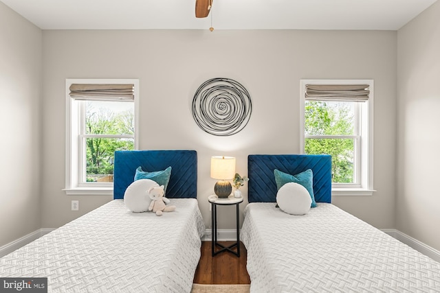bedroom featuring baseboards, a ceiling fan, wood finished floors, and multiple windows