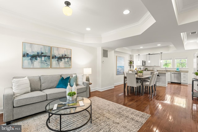 living room featuring crown molding, a tray ceiling, hardwood / wood-style flooring, and visible vents