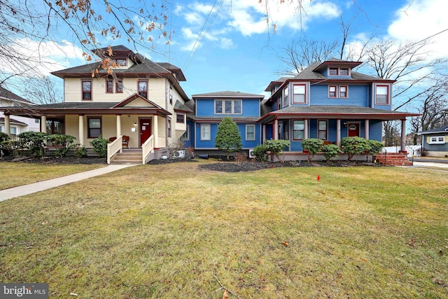 american foursquare style home with roof with shingles, a porch, and a front yard