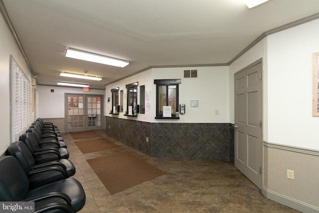interior space featuring visible vents, a wainscoted wall, ornamental molding, and french doors