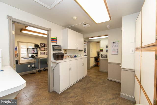kitchen featuring white cabinets, light countertops, and baseboards