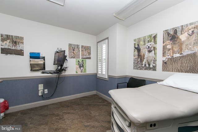 interior space with wainscoting, baseboards, and stone finish floor