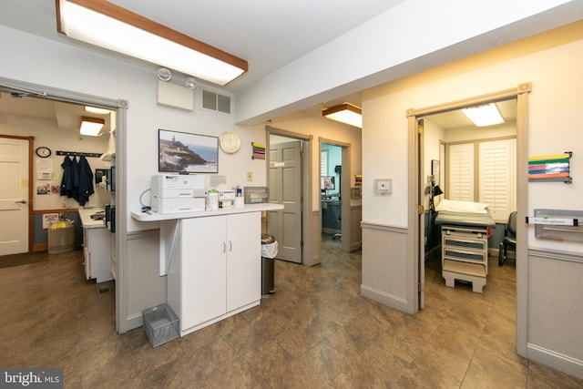 kitchen featuring light countertops, visible vents, white cabinetry, and wainscoting