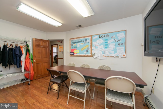 dining space featuring baseboard heating, wood finished floors, and visible vents