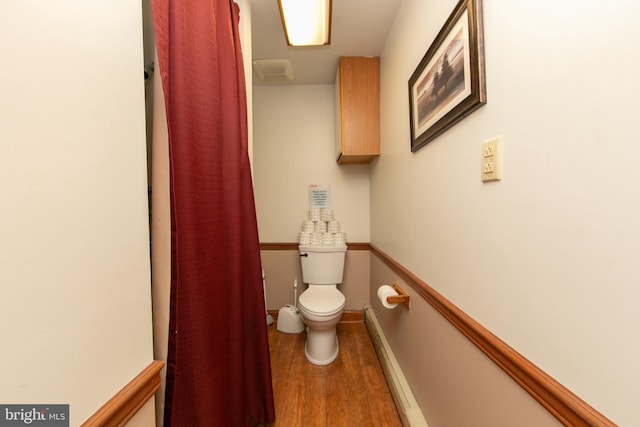 bathroom featuring baseboards, wood finished floors, and toilet