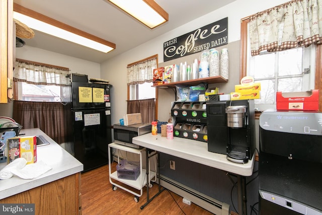 kitchen featuring baseboard heating, a sink, wood finished floors, stainless steel microwave, and freestanding refrigerator
