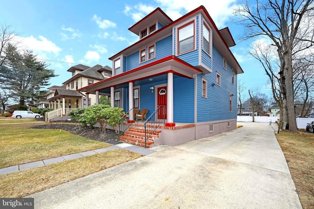traditional style home with concrete driveway, a front lawn, and covered porch