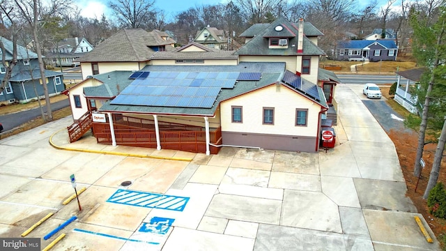 view of front of house with roof mounted solar panels, crawl space, a residential view, and a shingled roof