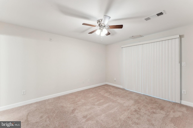 carpeted spare room with visible vents, a ceiling fan, and baseboards