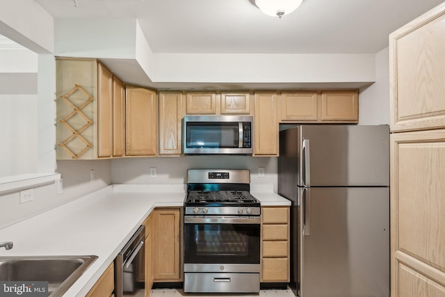 kitchen with light countertops, appliances with stainless steel finishes, a sink, and light brown cabinets