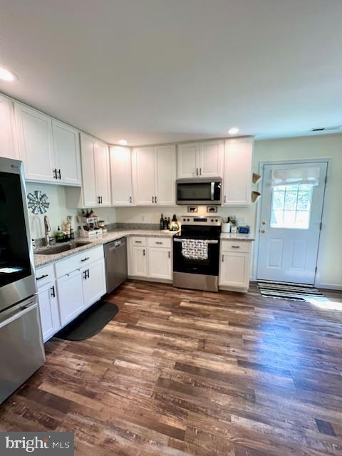 kitchen featuring stainless steel appliances, a sink, white cabinets, dark wood finished floors, and recessed lighting