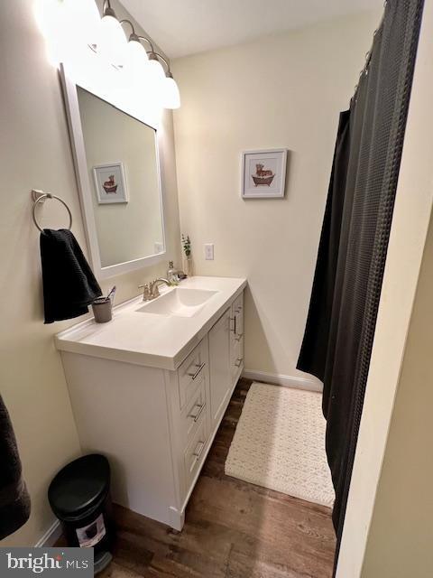 full bathroom with wood finished floors, vanity, and baseboards