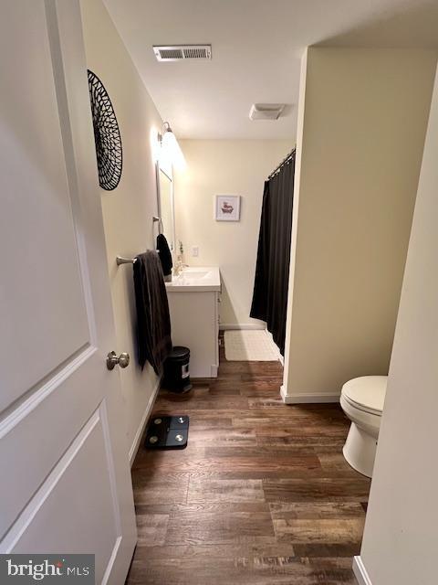 full bath featuring wood finished floors, toilet, vanity, curtained shower, and baseboards