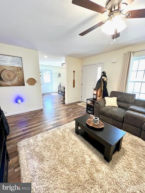 living area featuring wood finished floors, plenty of natural light, baseboards, and ceiling fan