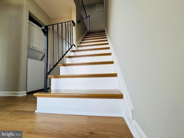 stairway featuring baseboards, wood finished floors, and visible vents