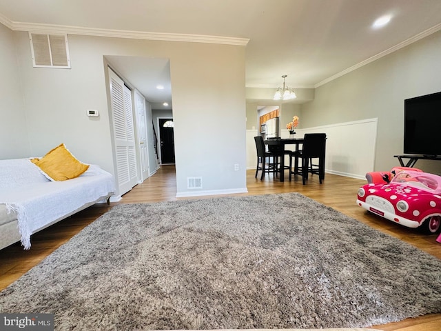 living room with visible vents, ornamental molding, wood finished floors, and a notable chandelier