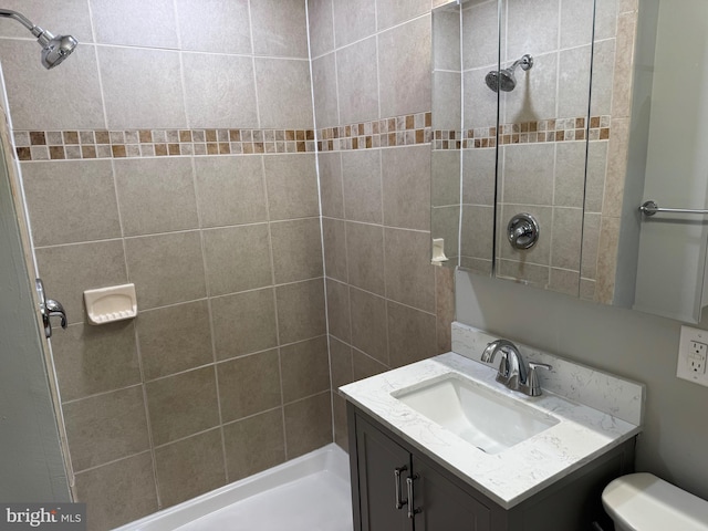 bathroom featuring toilet, a tile shower, and vanity