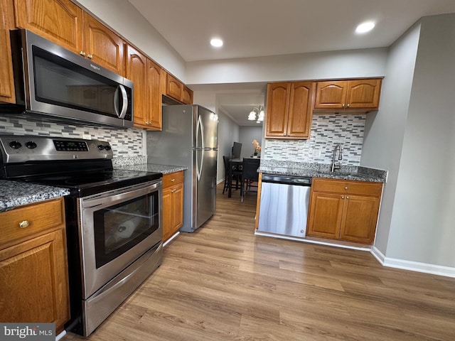kitchen with baseboards, stainless steel appliances, and light wood-type flooring